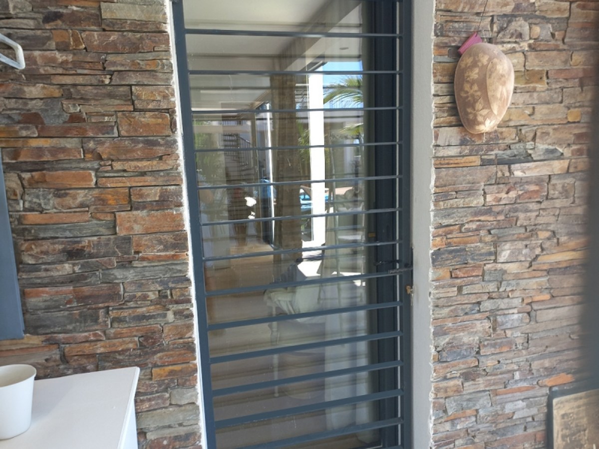 Grille de porte de sécurité installée devant une entrée vitrée