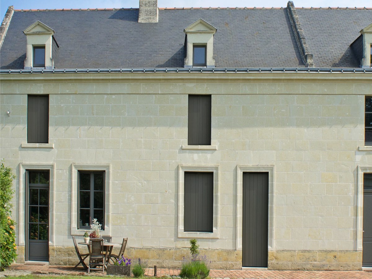 Persiennes de sécurité en aluminium sur une maison en pierre