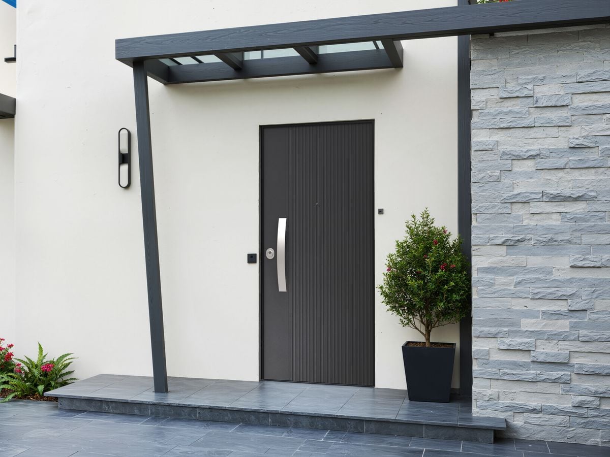 Porte blindée noire rainurée, sous un auvent vitré